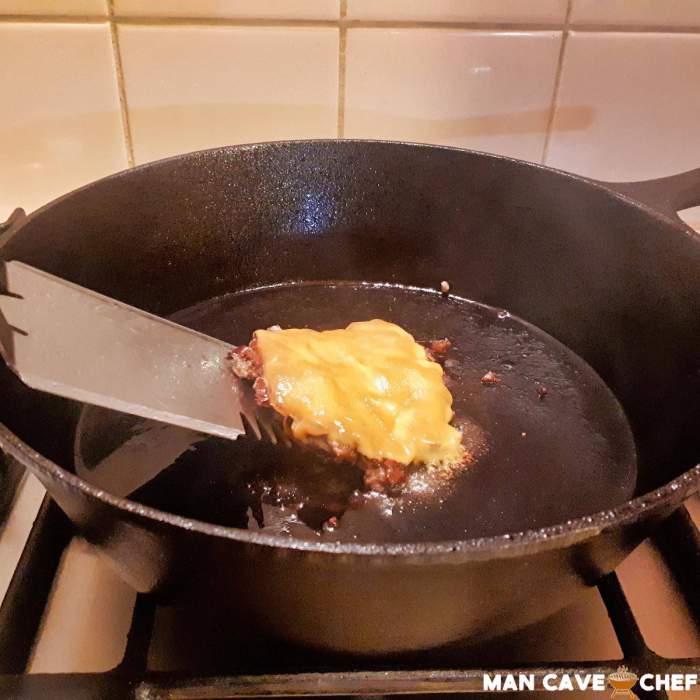 Melted cheese on smashed burger in pan